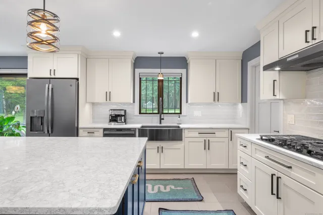 a kitchen with stainless steel appliances granite countertop a stove a sink dishwasher and a refrigerator with wooden floor