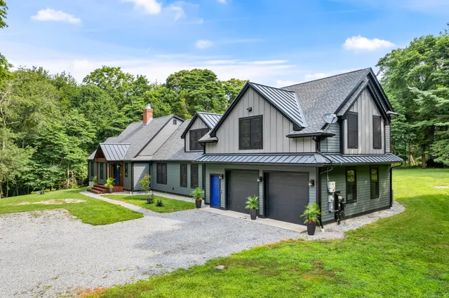 a view of a house with a yard and large tree