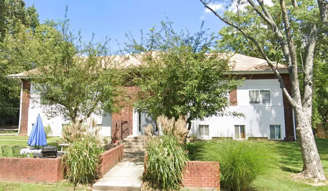 a view of a yard in front of a house with large tree