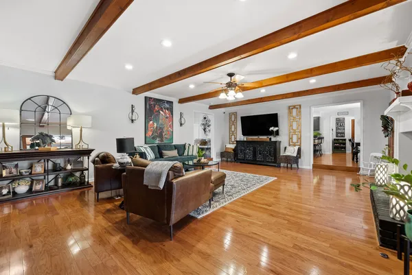 a kitchen with stainless steel appliances kitchen island granite countertop a refrigerator a stove a sink a dining table and chairs with wooden floor