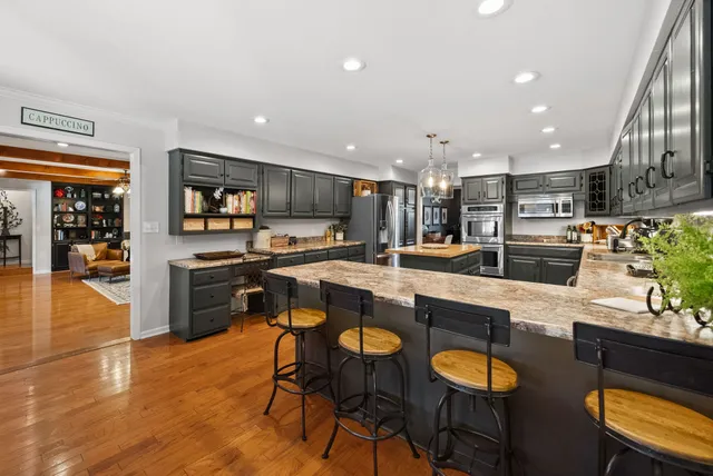 a kitchen with stainless steel appliances granite countertop a stove top oven a sink dishwasher and a refrigerator with wooden cabinets