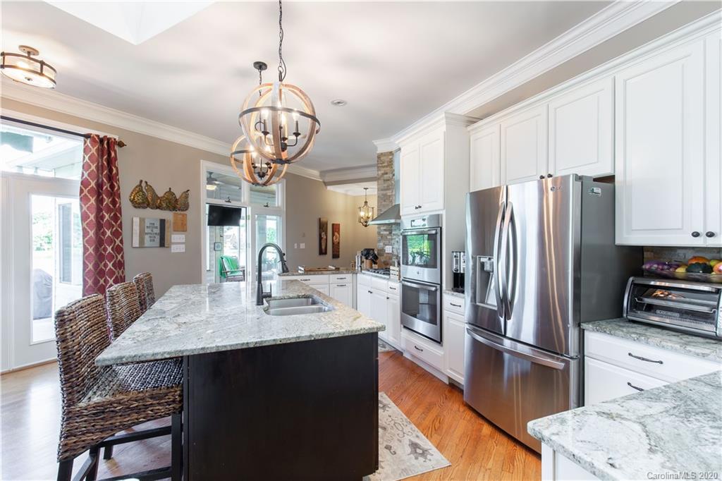 231 Pennington Road Rock Hill, SC 29732 - Photo 12 of 46 a kitchen with stainless steel appliances granite countertop a refrigerator a sink dishwasher a stove and a dining table with wooden floor