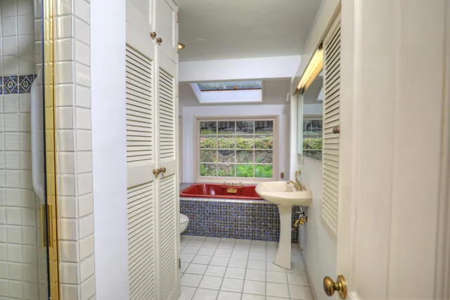 a bathroom with a sink a bathtub and next to a window