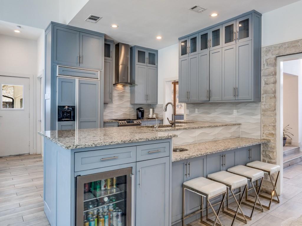 7326 Spring Valley Road Dallas, TX 75254 - Photo 11 of 25 Kitchen with light stone counters, wine cooler, glass insert cabinets, backsplash, and a peninsula