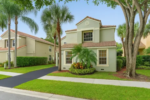 a front view of a house with a yard and palm trees