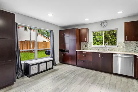a kitchen with wooden floors a sink a window and appliances