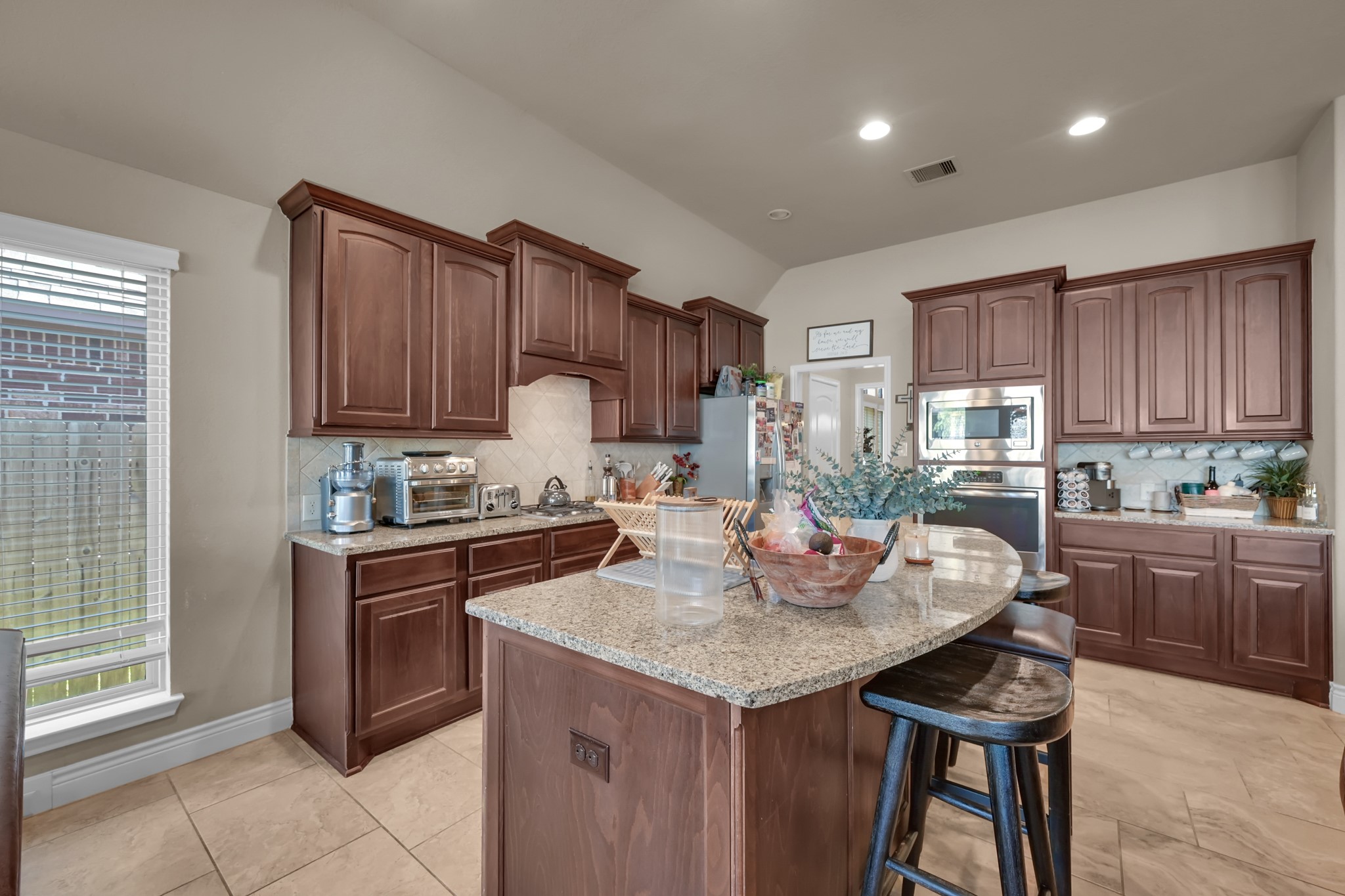 3814 Trophy Ridge Spring, TX 77386 - Photo 20 of 39 This kitchen features rich wood cabinetry, granite countertops, and an island. It includes modern stainless steel appliances and ample natural light, creating a warm and functional space.