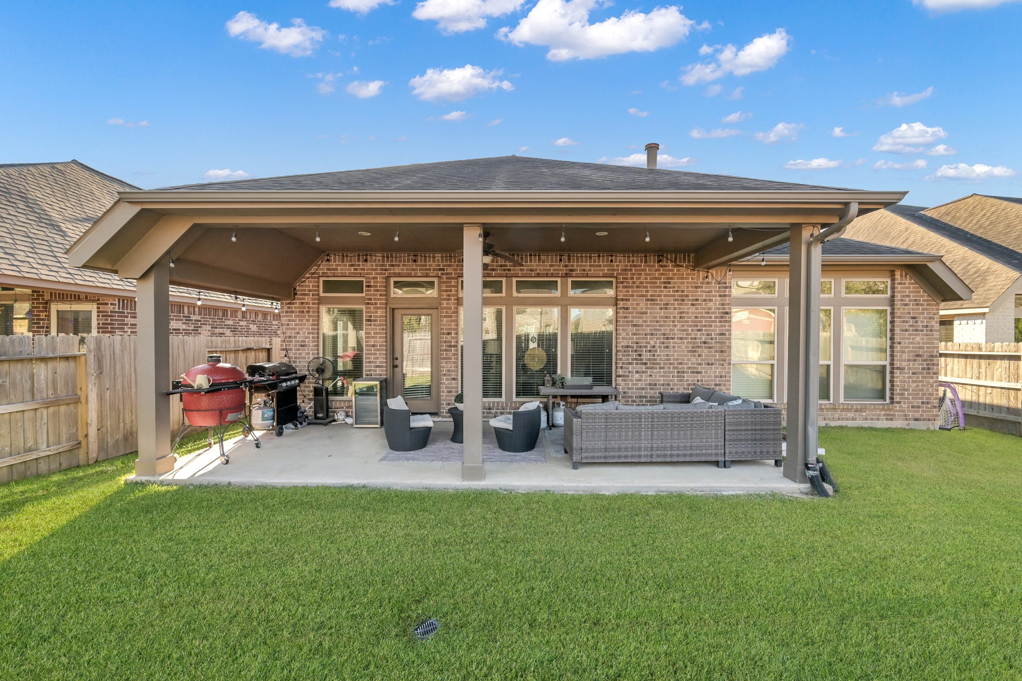 3814 Trophy Ridge Spring, TX 77386 - Photo 36 of 39 This photo showcases a spacious backyard patio with a covered seating area, perfect for entertaining. It features a brick exterior, ample space for outdoor furniture, and a well-maintained lawn, ideal for relaxing or hosting gatherings.