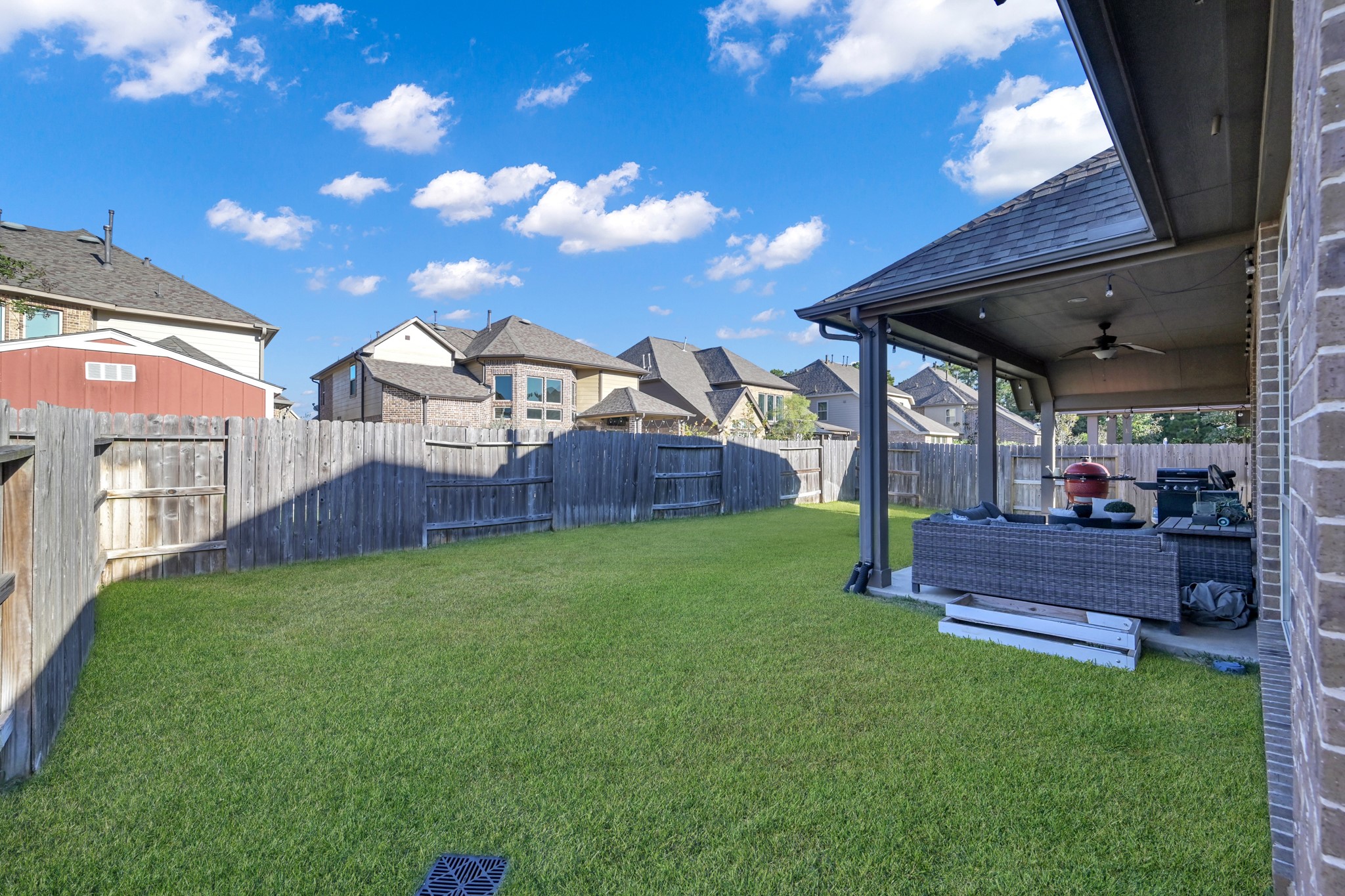 3814 Trophy Ridge Spring, TX 77386 - Photo 38 of 39 Spacious backyard with a well-maintained lawn, wooden privacy fence, and a covered patio area perfect for outdoor gatherings. Ideal for entertaining and enjoying the outdoors.