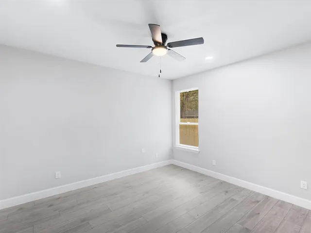 an empty room with a window and ceiling fan