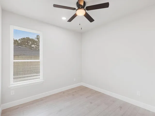 an empty room with a window and a fan