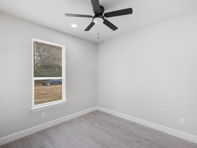 an empty room with a window and a ceiling fan