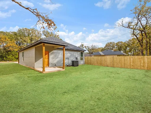 a view of a backyard with plants and large tree