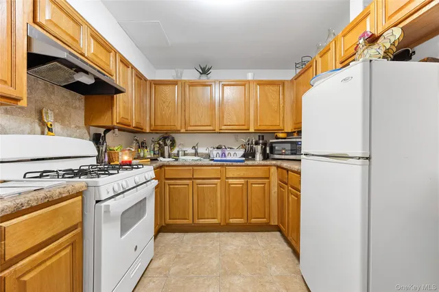 a kitchen with stainless steel appliances granite countertop a refrigerator sink stove and white cabinets