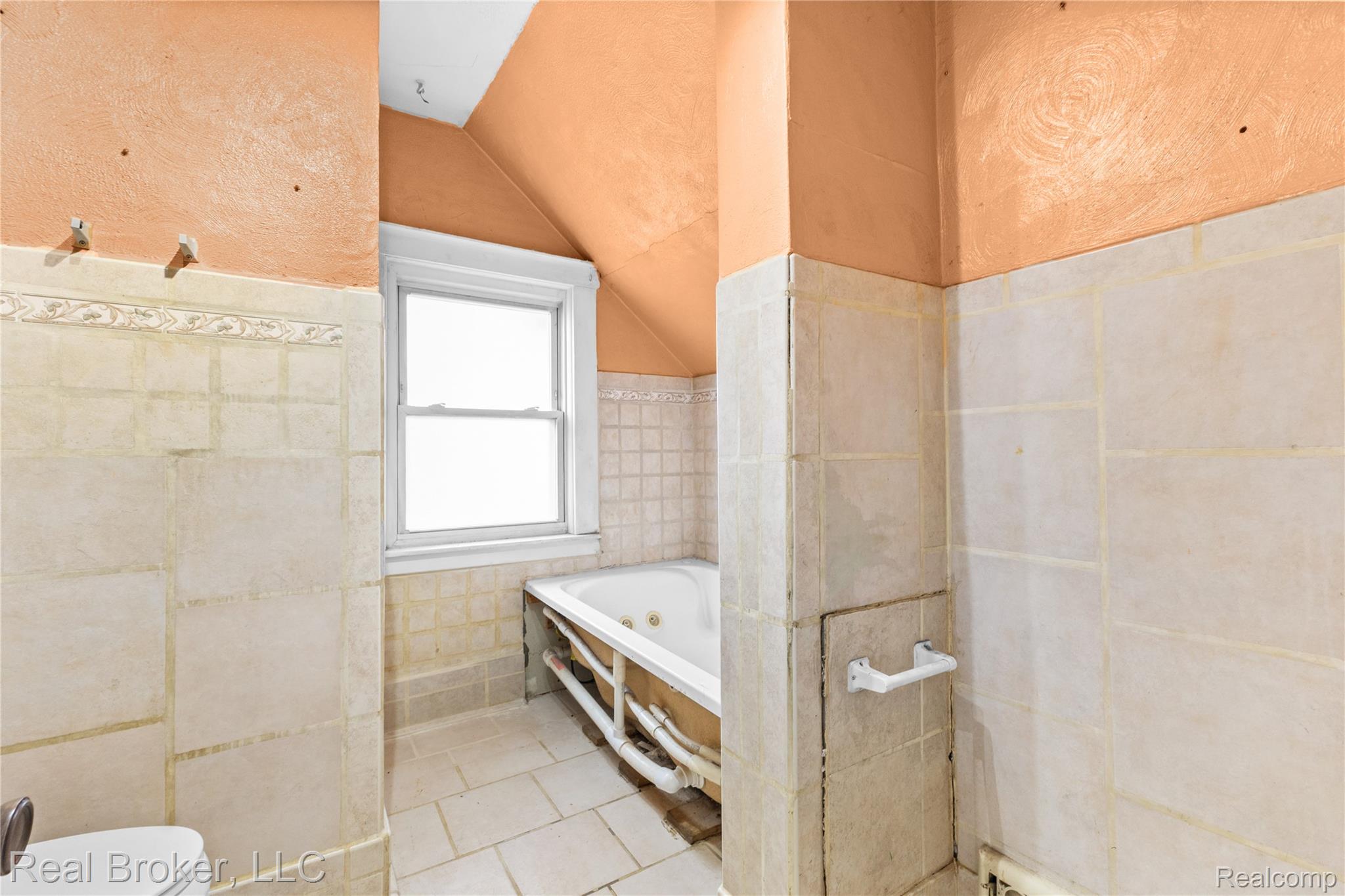 352 Perry Street Pontiac, MI 48342 - Photo 20 of 30 Bathroom featuring tile walls, vaulted ceiling, a bath, wainscoting, and light tile patterned floors