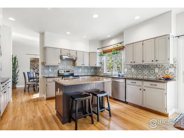 a kitchen with stainless steel appliances granite countertop wooden cabinets a sink a stove a dining table and chairs