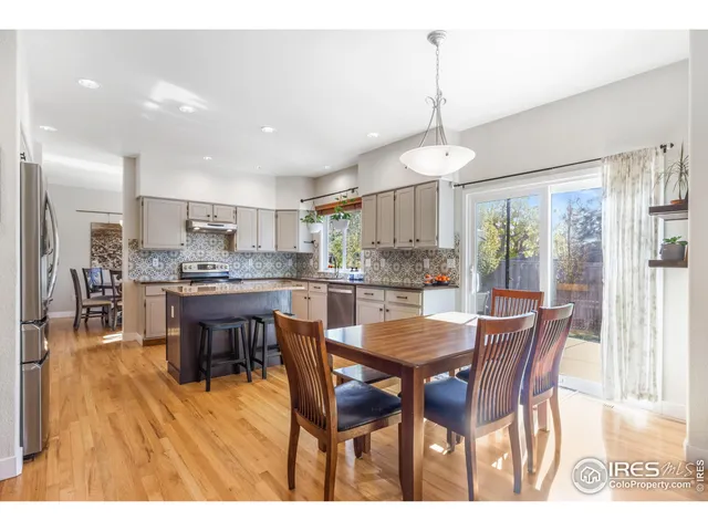 a dining room with stainless steel appliances kitchen island granite countertop a dining table chairs and white cabinets