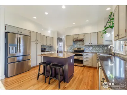 a kitchen with kitchen island granite countertop wooden floors appliances and refrigerator