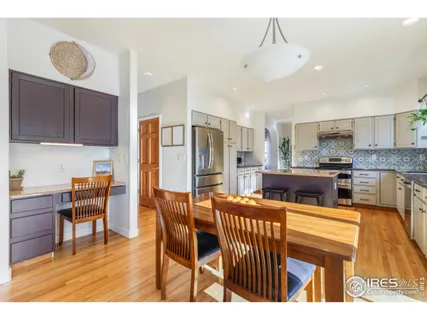 a open kitchen with stainless steel appliances kitchen island granite countertop a refrigerator a stove a sink dishwasher with a dining table and chairs with wooden floor