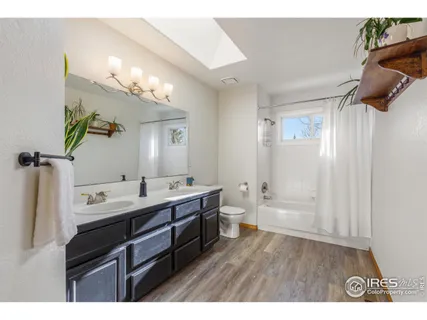 a bathroom with a double vanity sink a large mirror and a bathtub