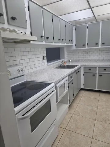 a kitchen with stainless steel appliances granite countertop a stove a sink and white cabinets