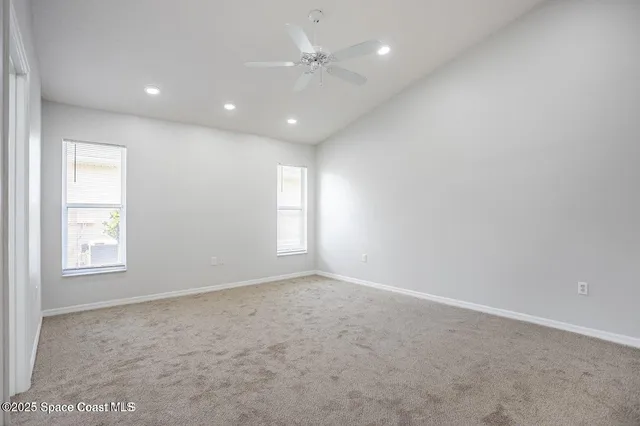 an empty room with windows and ceiling fan