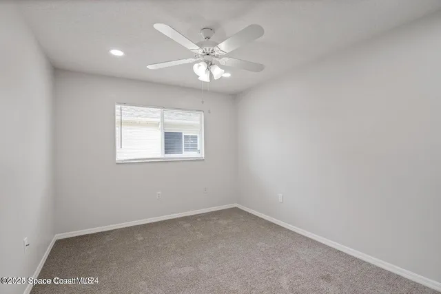 an empty room with a window and a fan