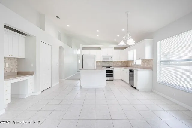 a large white kitchen with cabinets and a refrigerator