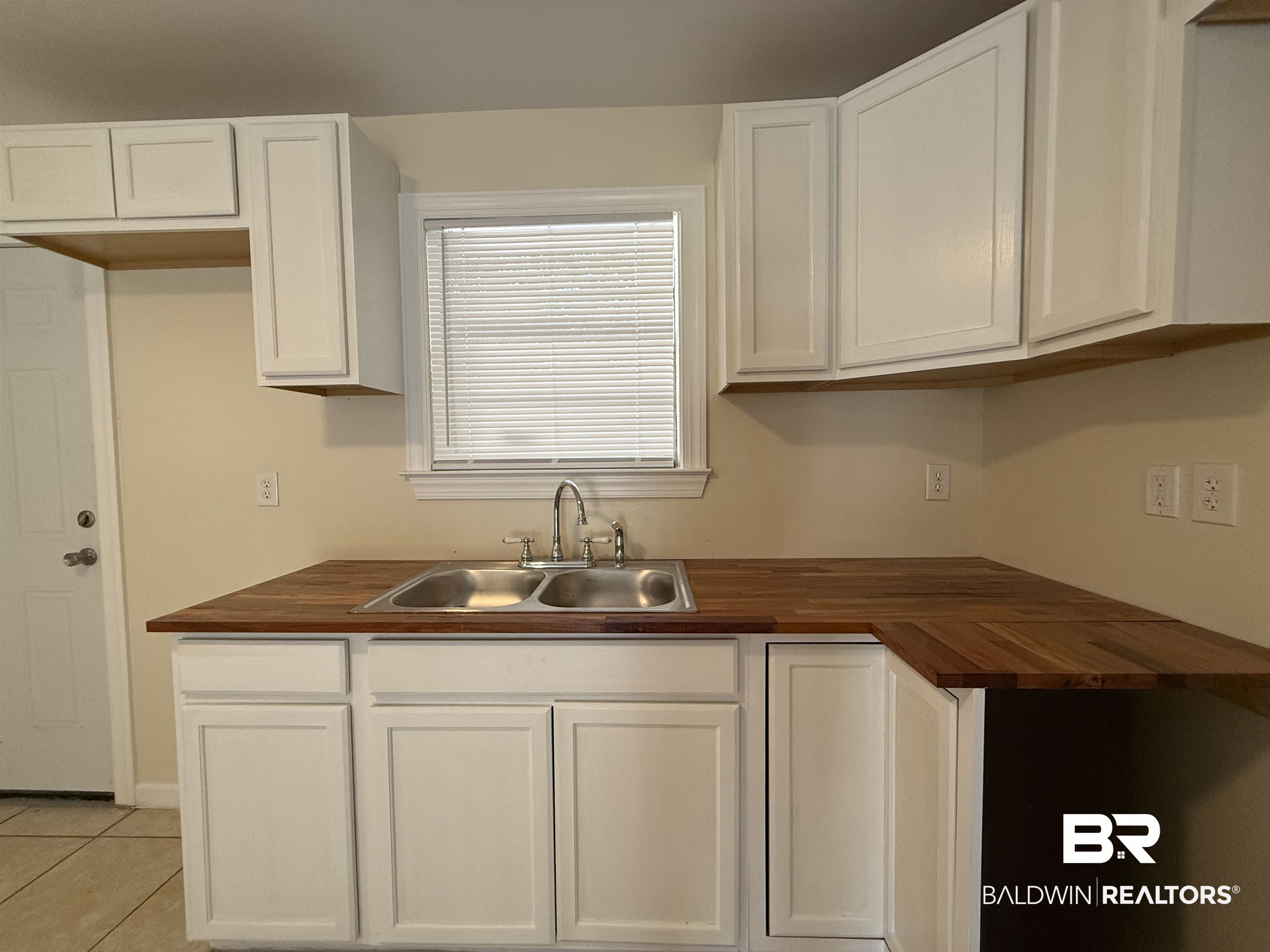 320 E Street Prichard, AL 36610 - Photo 14 of 16 Kitchen featuring butcher block countertops, sink, light tile patterned floors, and white cabinetry