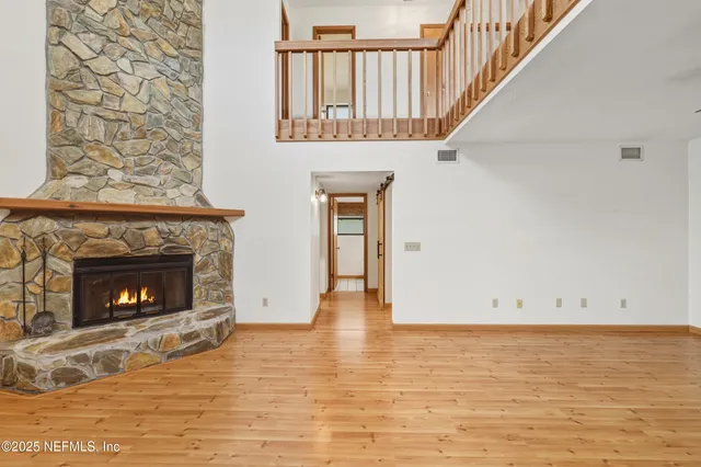 a view of an empty room with wooden floor fireplace and a window