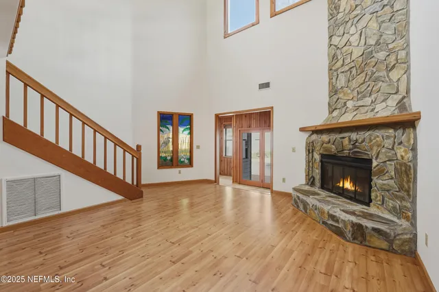 a view of an empty room with wooden floor fireplace and a window
