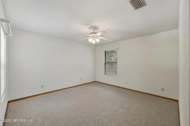 an empty room with a window and a ceiling fan
