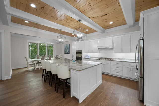 a large kitchen with kitchen island a white cabinets and wooden floor