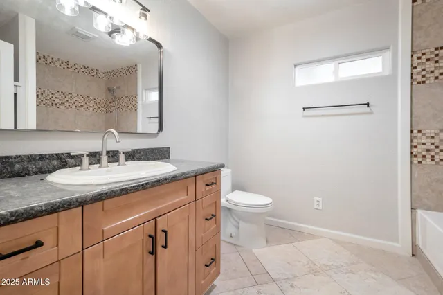 a bathroom with a granite countertop sink a toilet and a mirror