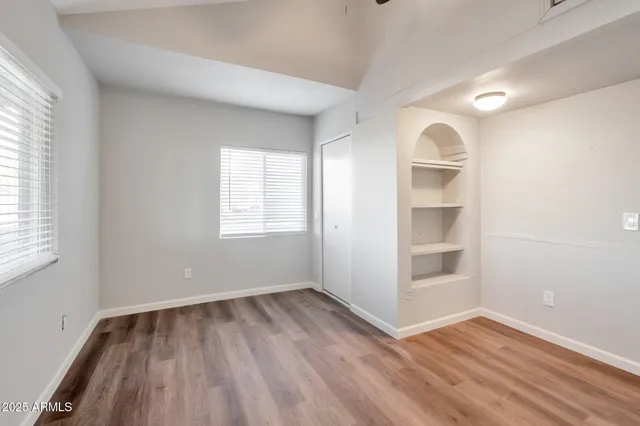 an empty room with wooden floor and windows
