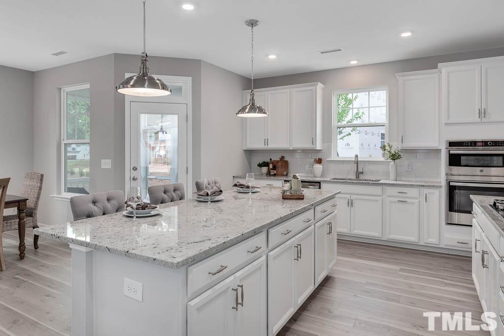112 Thrower Lane Garner, NC 27529 - Photo 11 of 38 a kitchen with sink stove and white cabinets with wooden floor