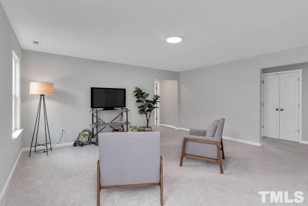 112 Thrower Lane Garner, NC 27529 - Photo 20 of 38 a living room with furniture a flat screen tv and a lamp