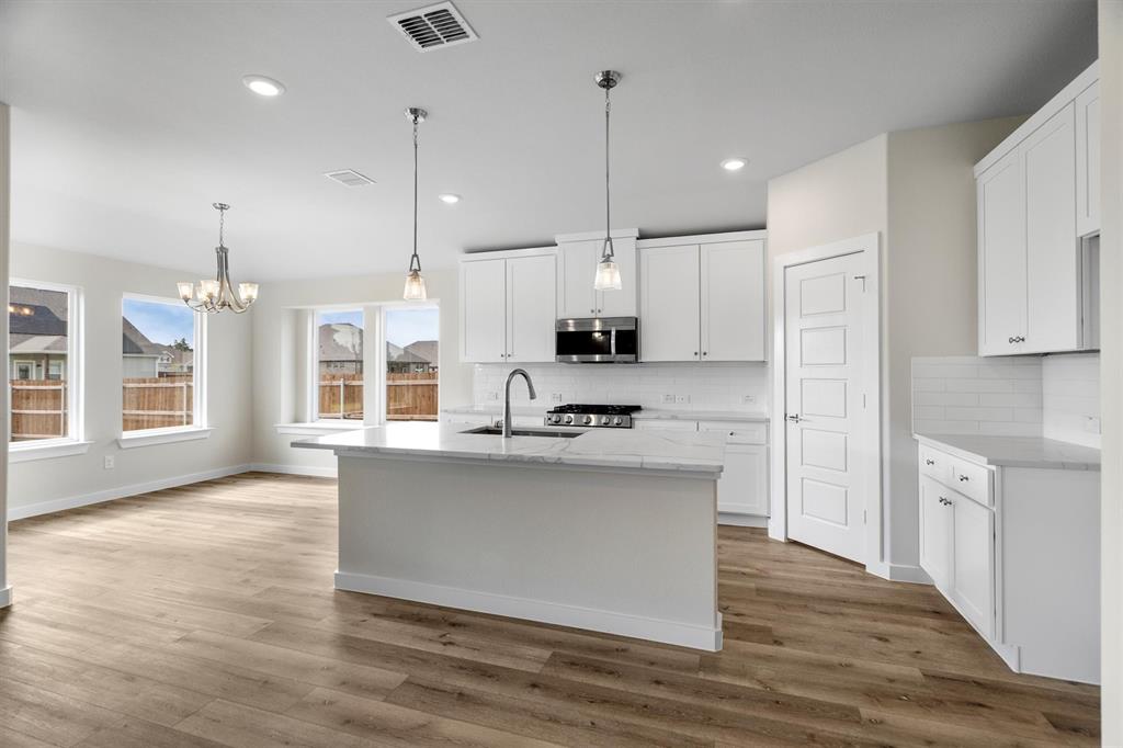 623 Kyle Drive Tioga, TX 76271 - Photo 11 of 40 a kitchen with stainless steel appliances granite countertop a sink a stove a refrigerator and white cabinets with wooden floor