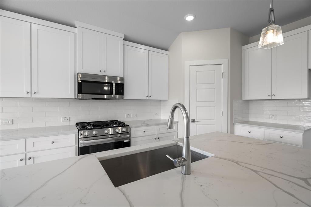 623 Kyle Drive Tioga, TX 76271 - Photo 18 of 40 a kitchen with granite countertop a stove a sink and a microwave