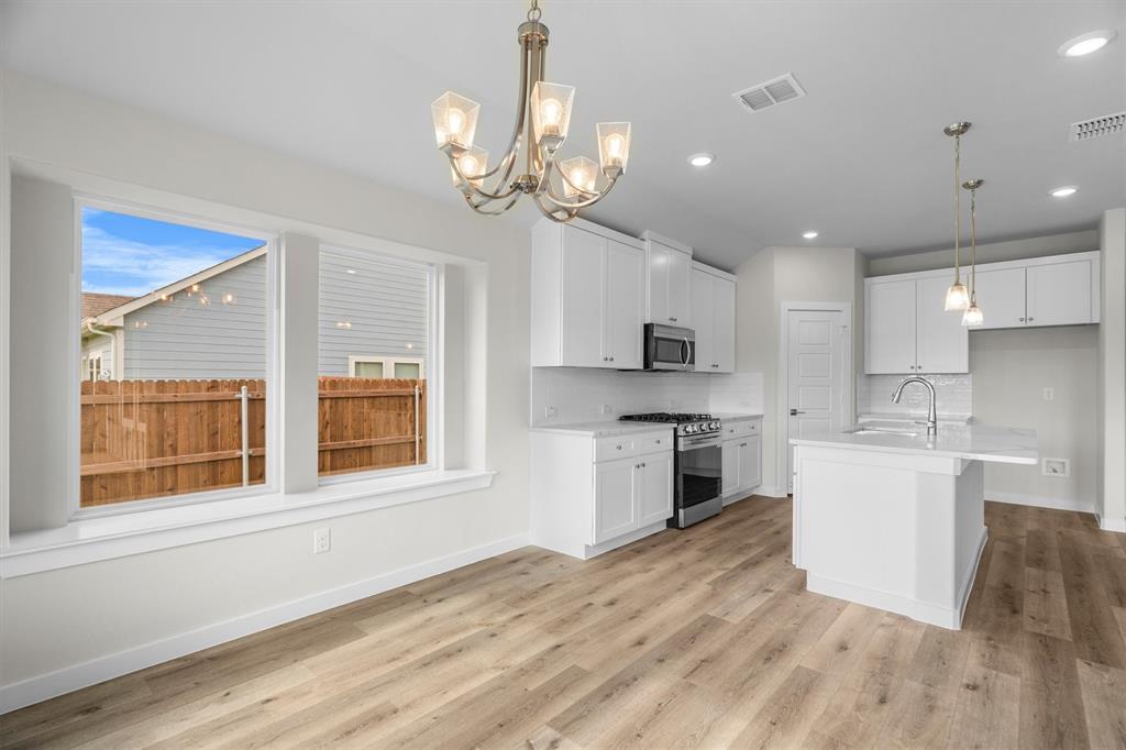 623 Kyle Drive Tioga, TX 76271 - Photo 20 of 40 a large kitchen with kitchen island a stove a sink dishwasher a microwave oven and a dining table with wooden floor