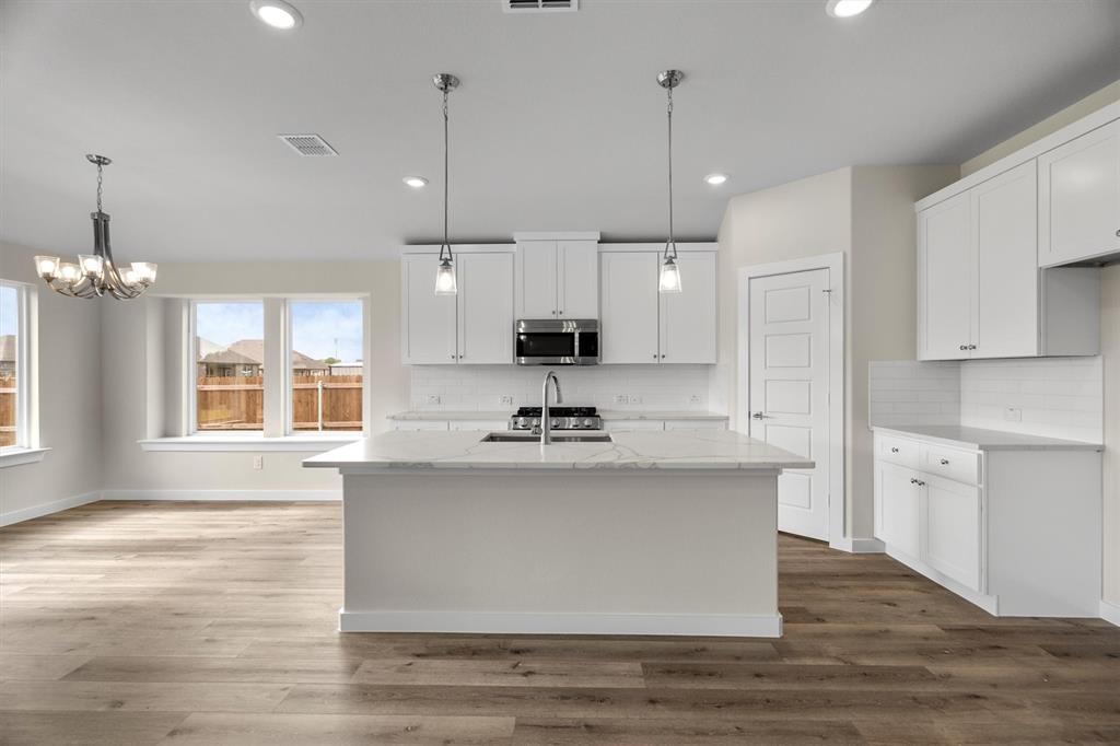 623 Kyle Drive Tioga, TX 76271 - Photo 10 of 40 a view of a kitchen with kitchen island a sink wooden floor and a window