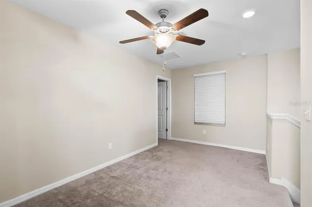 an empty room with ceiling fan and window