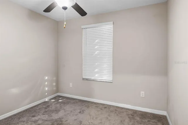 an empty room with a window and a fan