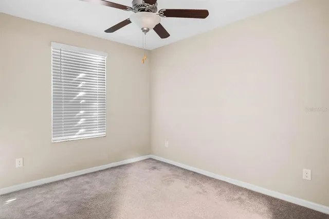 an empty room with a window and a fan