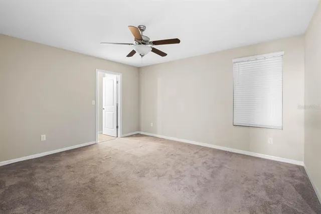 an empty room with a window and a fan