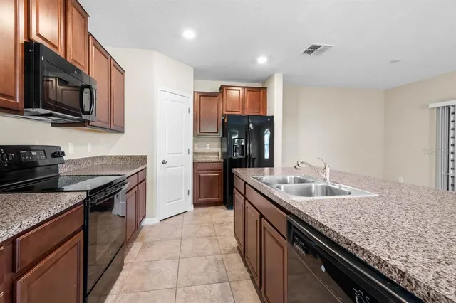 a kitchen with stainless steel appliances granite countertop a sink a stove and a wooden cabinets