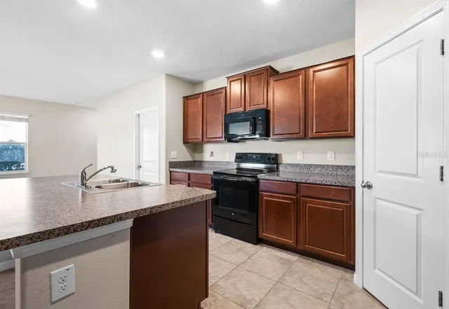 a kitchen with stainless steel appliances granite countertop a stove a sink and a microwave