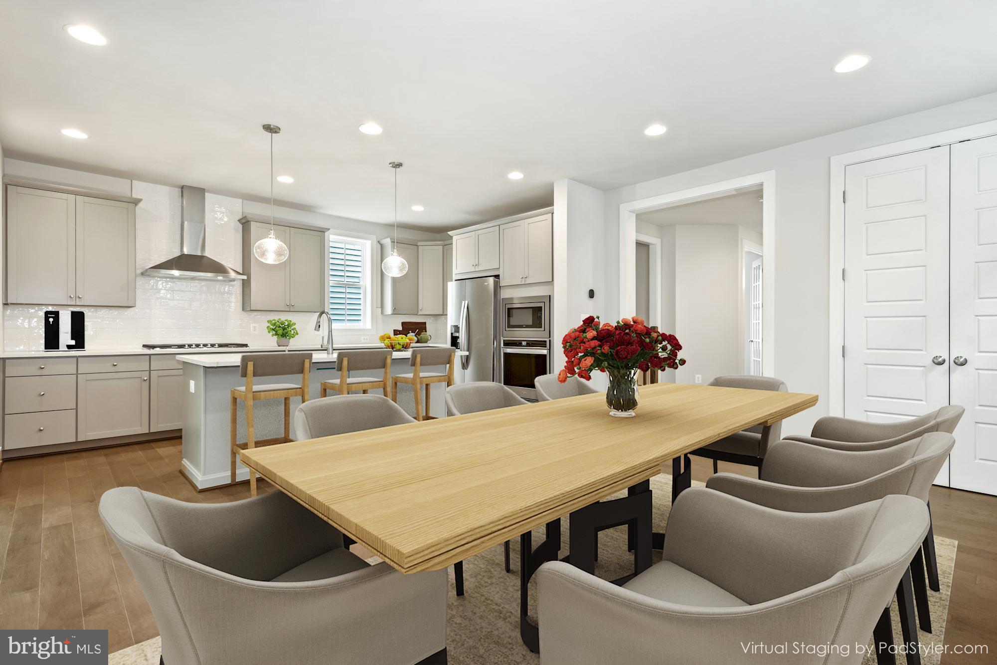 a living room with stainless steel appliances furniture a dining table and kitchen view