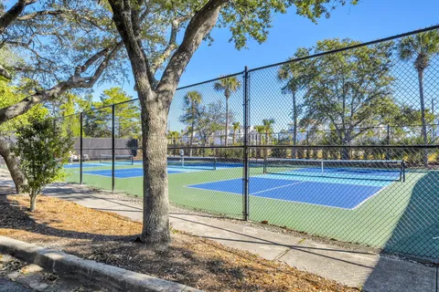 a view of a tennis ground with large trees