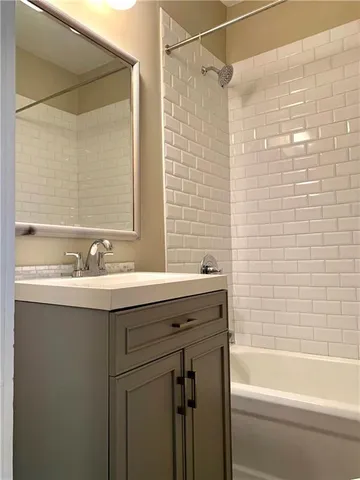 a bathroom with a granite countertop sink mirror bathtub and shower